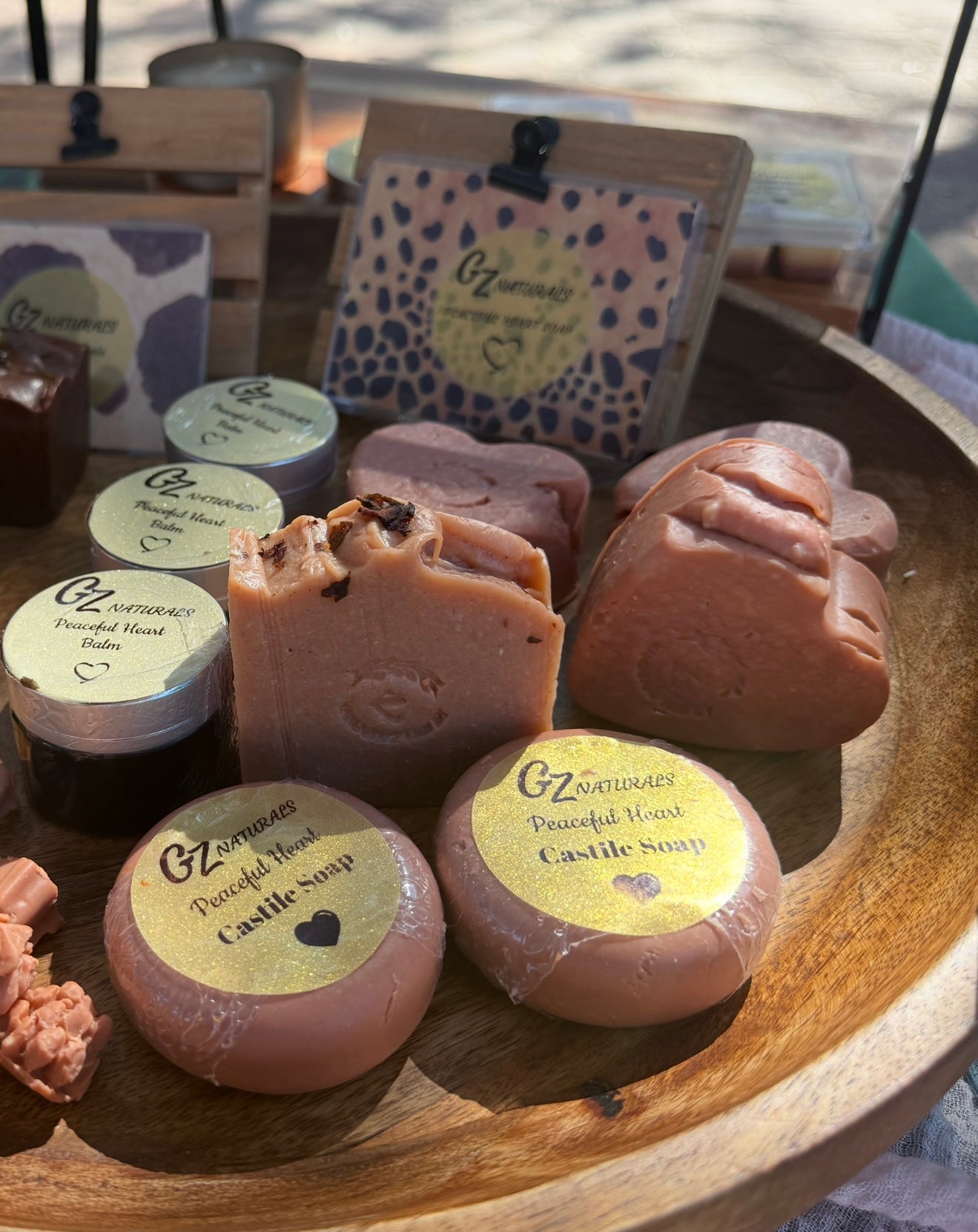 Collection of GZ Naturals castile soaps on a wooden tray with visible branding.